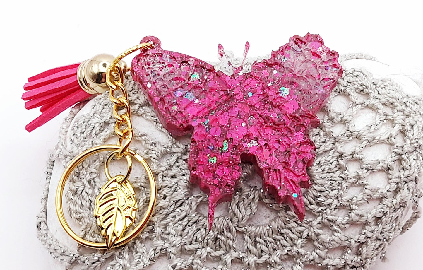 Porte-clés "Papillon" en résine époxy, paillettes roses fuchsia, posé sur un galet