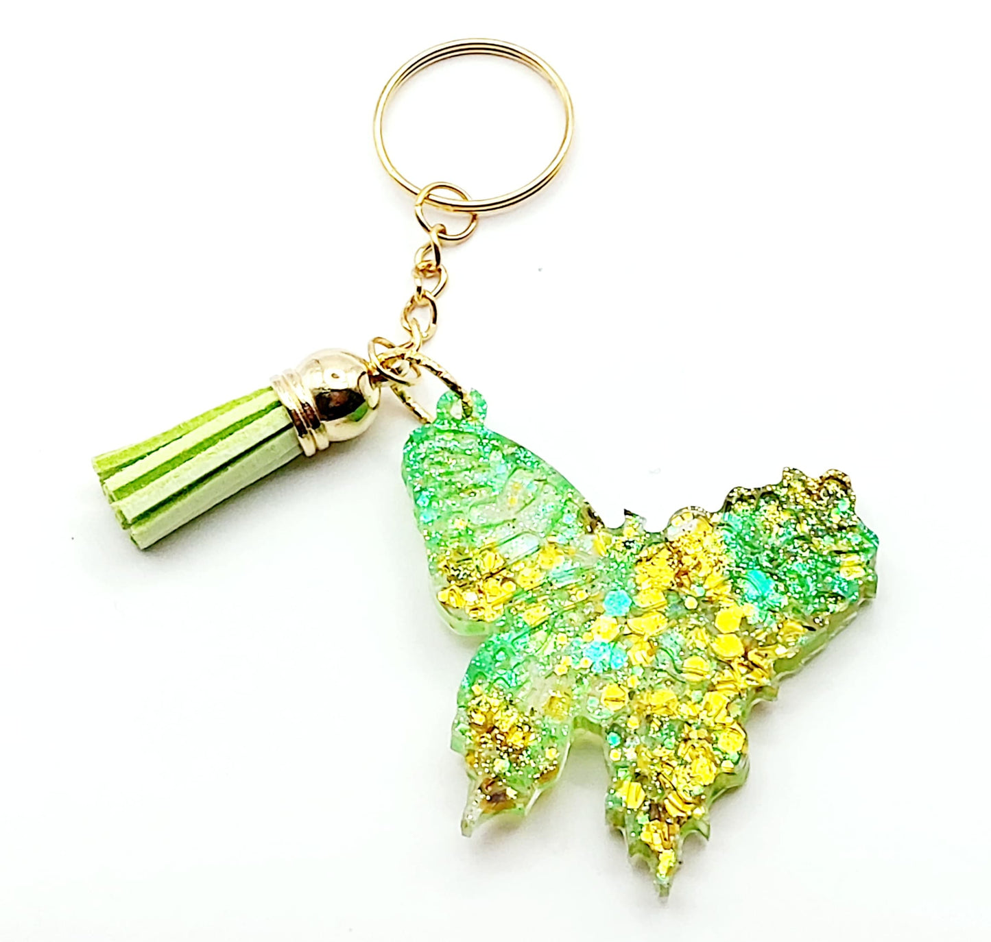 Porte-clés "Papillon" en résine époxy. Paillettes vertes et dorées, pompon gland vert, anneau doré.